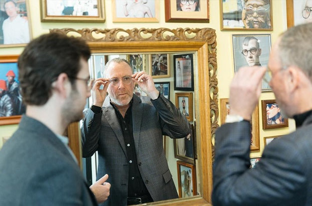 Man trying on glasses and looking in mirror