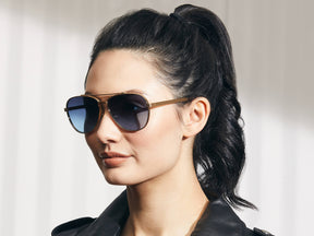 Model is wearing The SHAV SUN in Gold in size 62 with Denim Blue Tinted Lenses