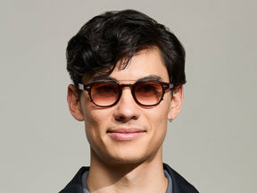 The Model is wearing The CLIPTOSH in Matte Black in size 46 with Root Beer Fade Tinted Lenses