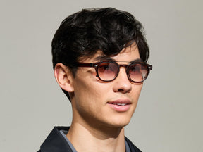 The Model is wearing The CLIPTOSH in Matte Black in size 46 with Root Beer Fade Tinted Lenses