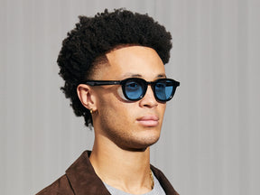 Model is wearing The DAHVEN in Black in size 47 with Celebrity Blue Tinted Lenses