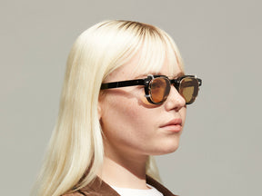 Model is wearing The DOLT CLIP in Gold in size 46 with Amber Tinted Lenses
