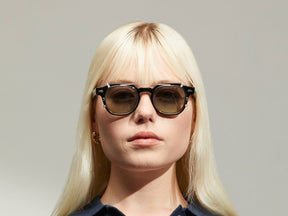 Model is wearing The DOLT CLIP in Gold in size 46 with Forest Wood Tinted Lenses