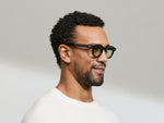 Model is wearing The DOLT in Black in size 46 with GREEN+ Lenses