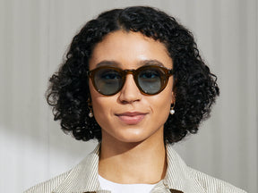 Model is wearing The KEPPE SUN in Olive Brown in size 48 with Mineral Blue Glass Lenses