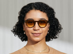Model is wearing The MAYDELA SUN in Olive Brown in size 49 with Chestnut Fade Tinted Lenses