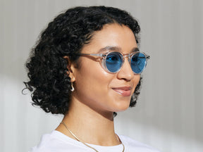 Model is wearing The MILTZEN in Crystal in size 49 with Celebrity Blue Tinted Lenses