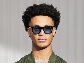 Model is wearing The RIZIK in Black in size 49 with Celebrity Blue Tinted Lenses