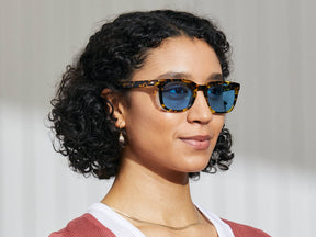 Model is wearing The SHIDDOCK SUN in Tokyo Tortoise in size 52 with Celebrity Blue Tinted Lenses
