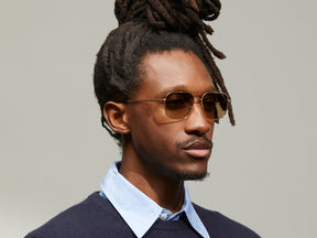 Model is wearing The SHTARKER SUN in Gold in size 57 with Cosmitan Brown Lenses