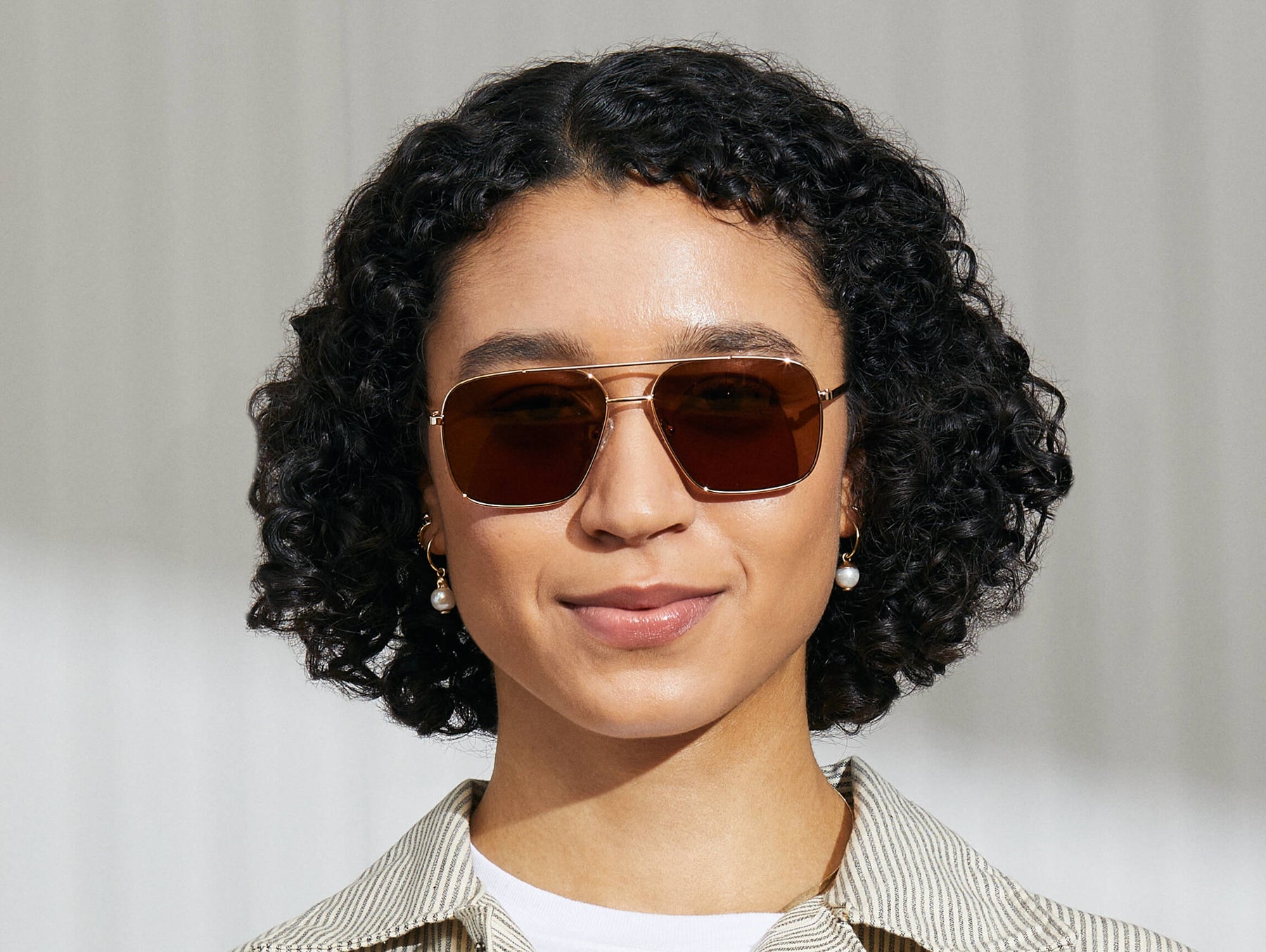 Model is wearing The SHTARKER SUN in Gold in size 57 with Cosmitan Brown Lenses