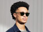 Model is wearing The TATAH SUN in Pine in size 50 with Calibar Green Glass Lenses