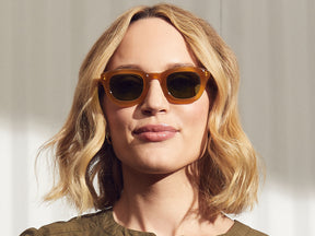 Model is wearing the TELENA SUN in Butterscotch in size 44 with Calibar Green Glass Lenses
