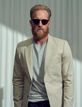 Model is wearing The GENUG SUN in Spot Tortoise/Gold in size 50 with Cosmitan Brown Glass Lenses