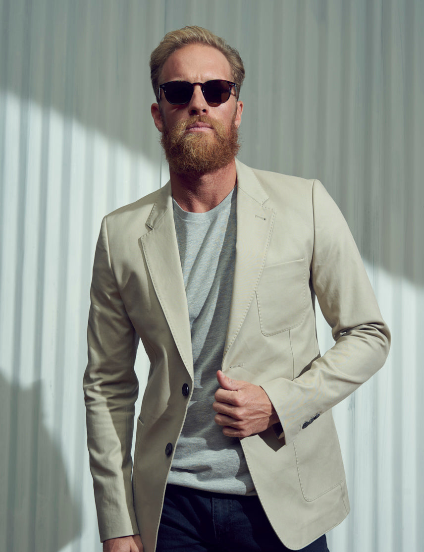 Model is wearing The GENUG SUN in Spot Tortoise/Gold in size 50 with Cosmitan Brown Glass Lenses