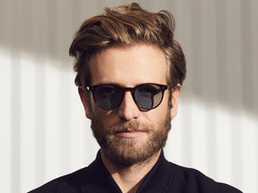 Model is wearing The GOLDA SUN in Spot Tortoise/Gold in size 49 with Blue Glass Lenses