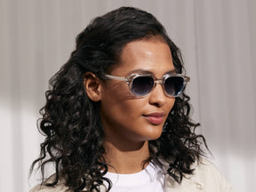 Model is wearing The GOOLAH SUN in Crystal in size 50 with Denim Blue Tinted Lenses
