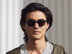 Model is wearing The MORRIS SUN in Matte Black in size 50 with Cosmitan Brown Glass Lenses
