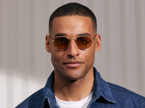 Model is wearing The SMENDRIK SUN in Gold in size 48 with Amber Tinted Lenses