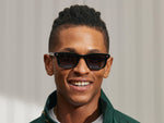 Model is wearing The KLUTZ SUN in Black in size 50 with Denim Blue Tinted Lenses